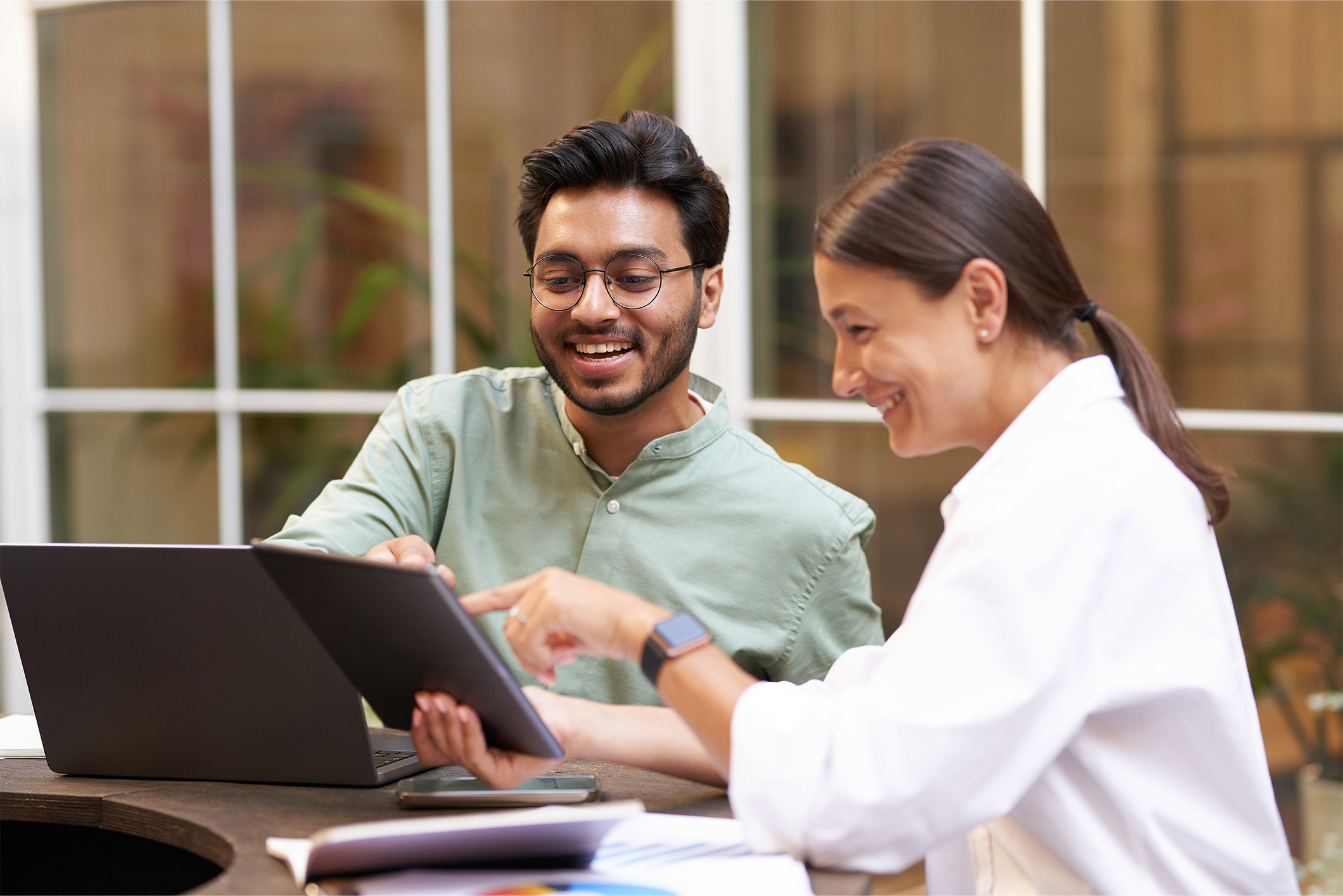 A woman is showing something on a tablet to her male colleague.