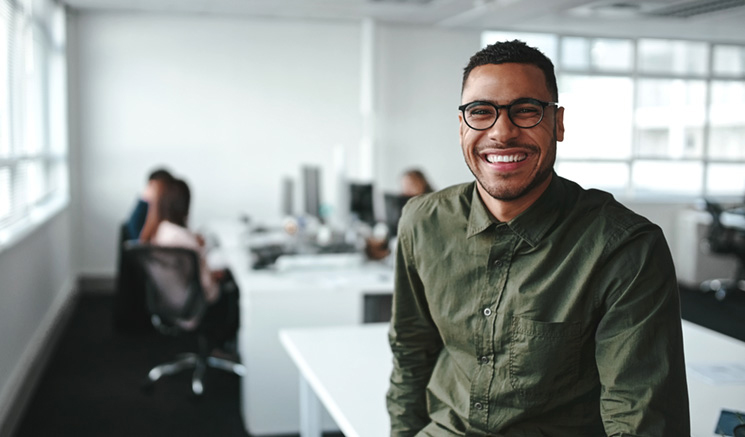 Smiling man wearing glasses in a computer lab