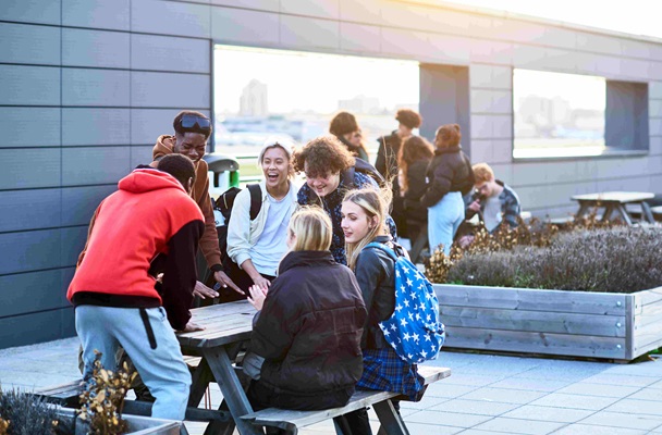 Male and female college students relaxing outside talking and laughing together, friendship, togetherness, happiness